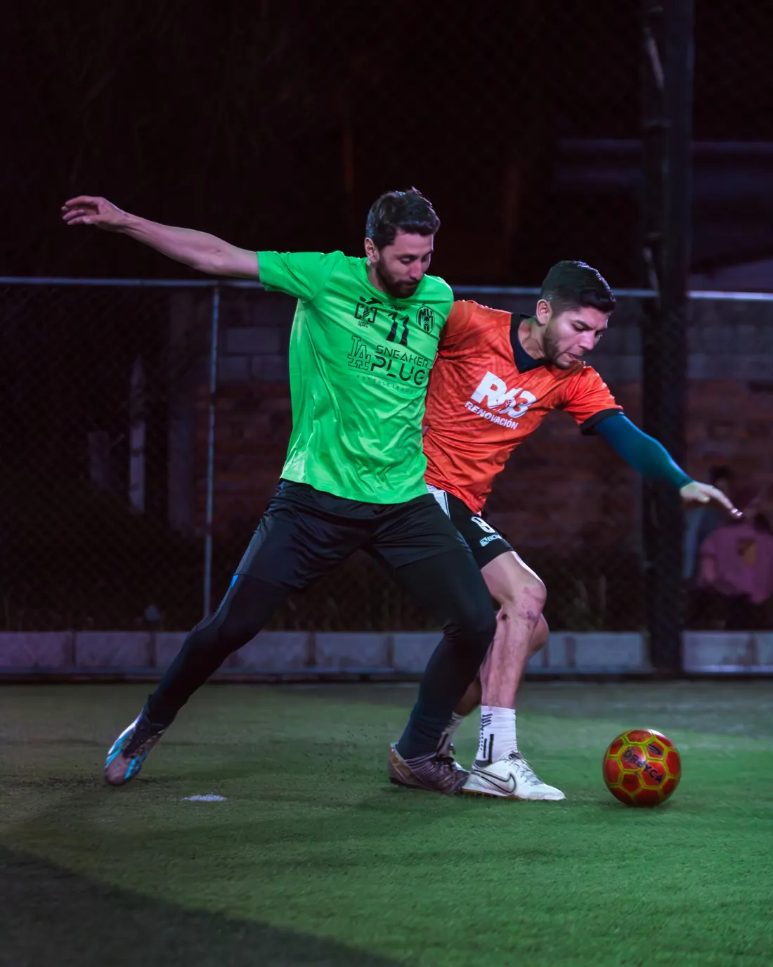 Dos jugadores disputando el balón de noche bajo las luces