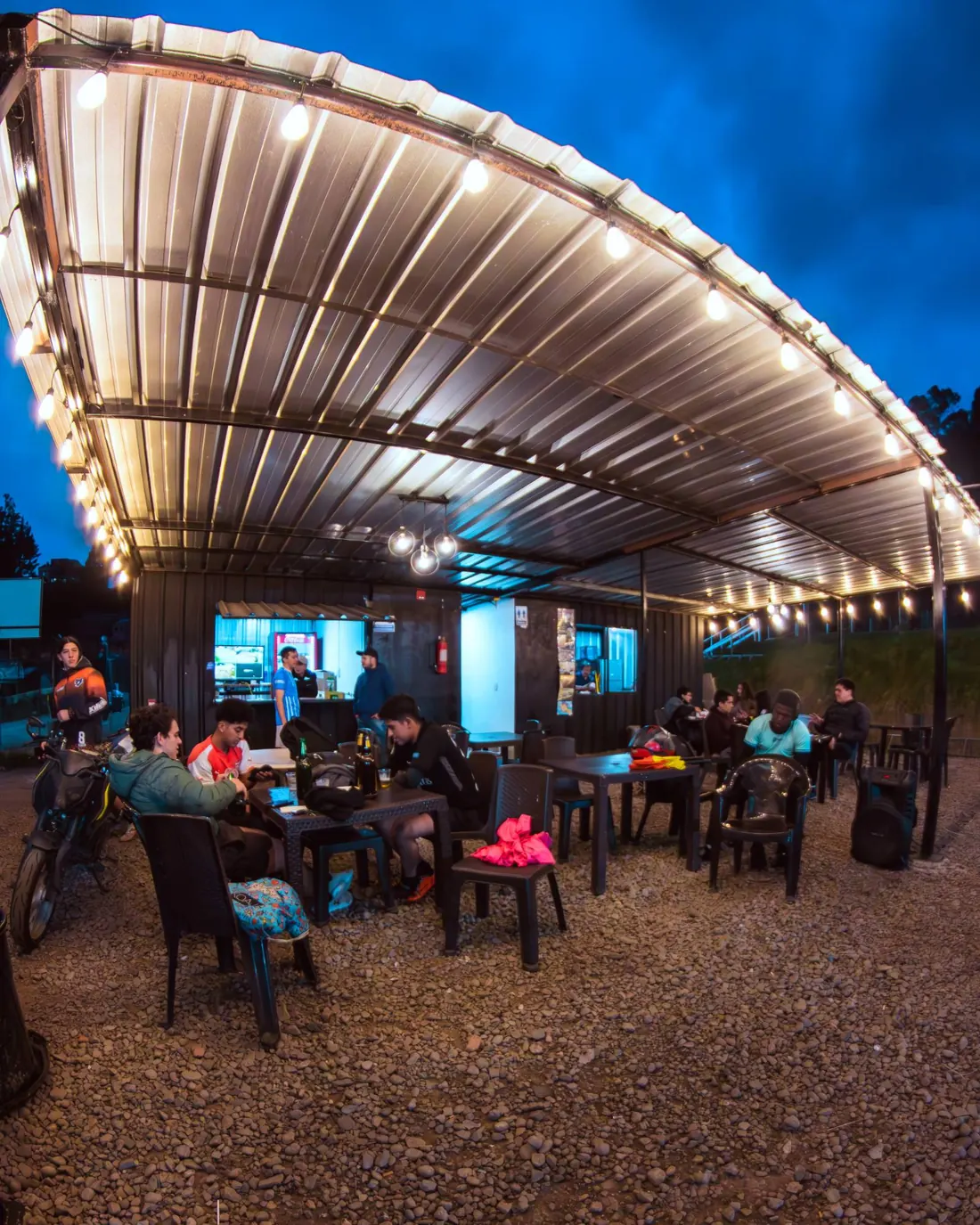 Área social con mesas bajo un techo de luces cálidas